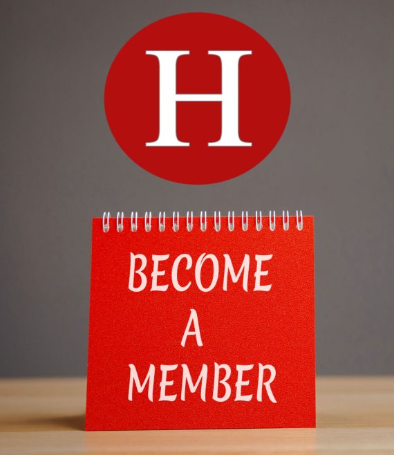 Red note card on wooden table white letters stating Become a Member. Red circle with a white letter H above note card